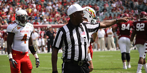 An NFL referree points to the end zone of a team that has committed a penalty. find a job with the NFL with Jobs in Sports.