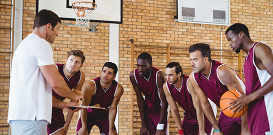 College basketball coach in a huddle with the team doing his job by guiding his team.